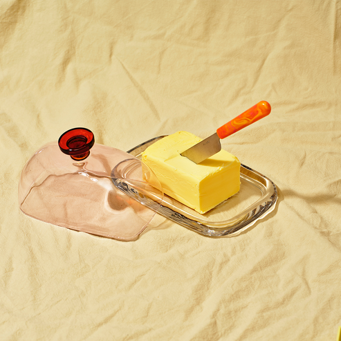 Butter dish with a stick of butter and a knife on a beige background